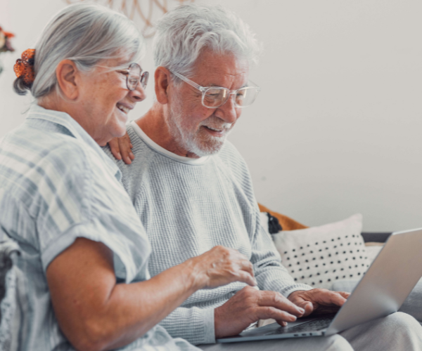 A mature women waving at the computer monitor