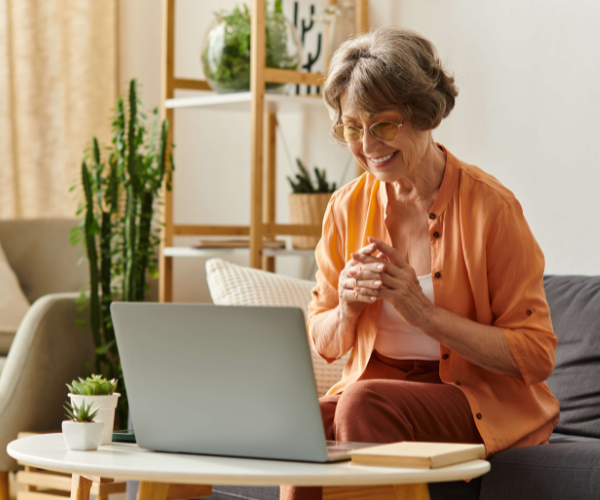 A mature women waving at the computer monitor