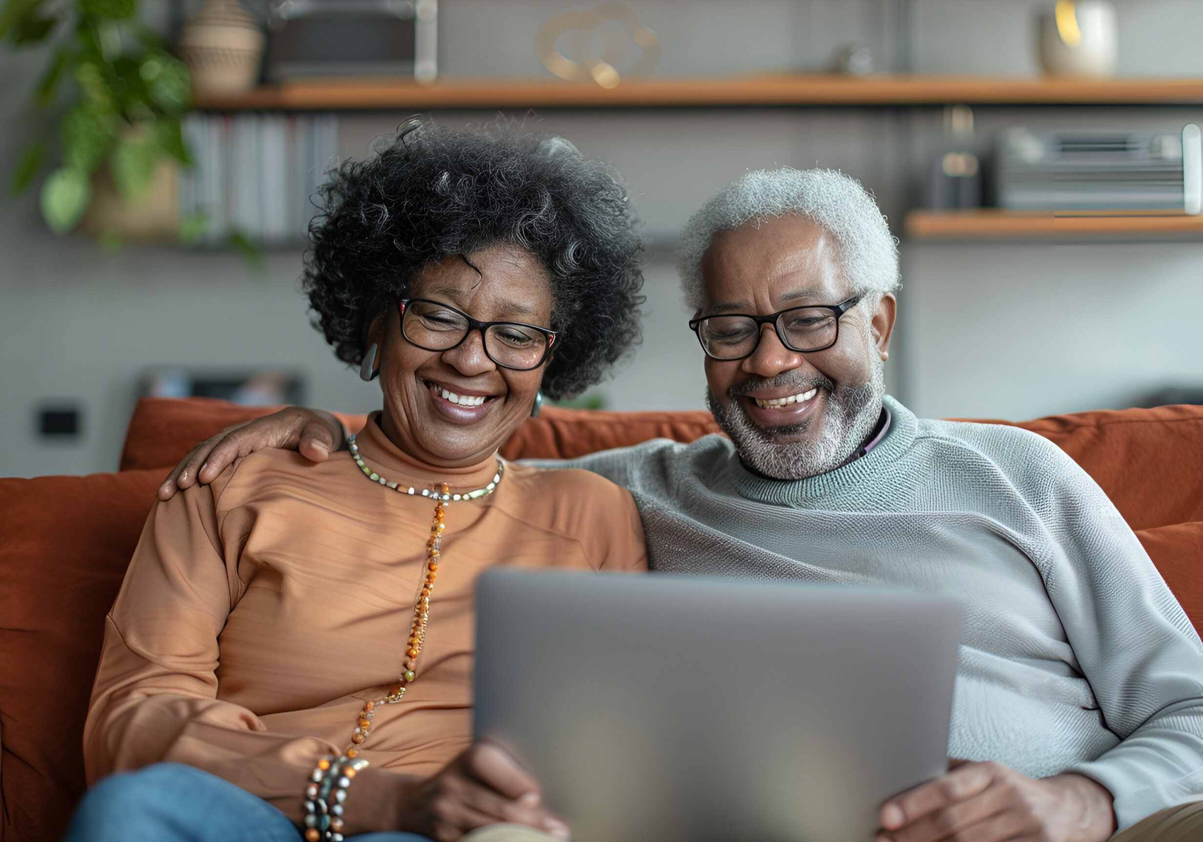 Happy mixed race couple of old people enjoying online entertainment with laptop, using Internet technology, application, communication, looking at computer screen together, laughing
